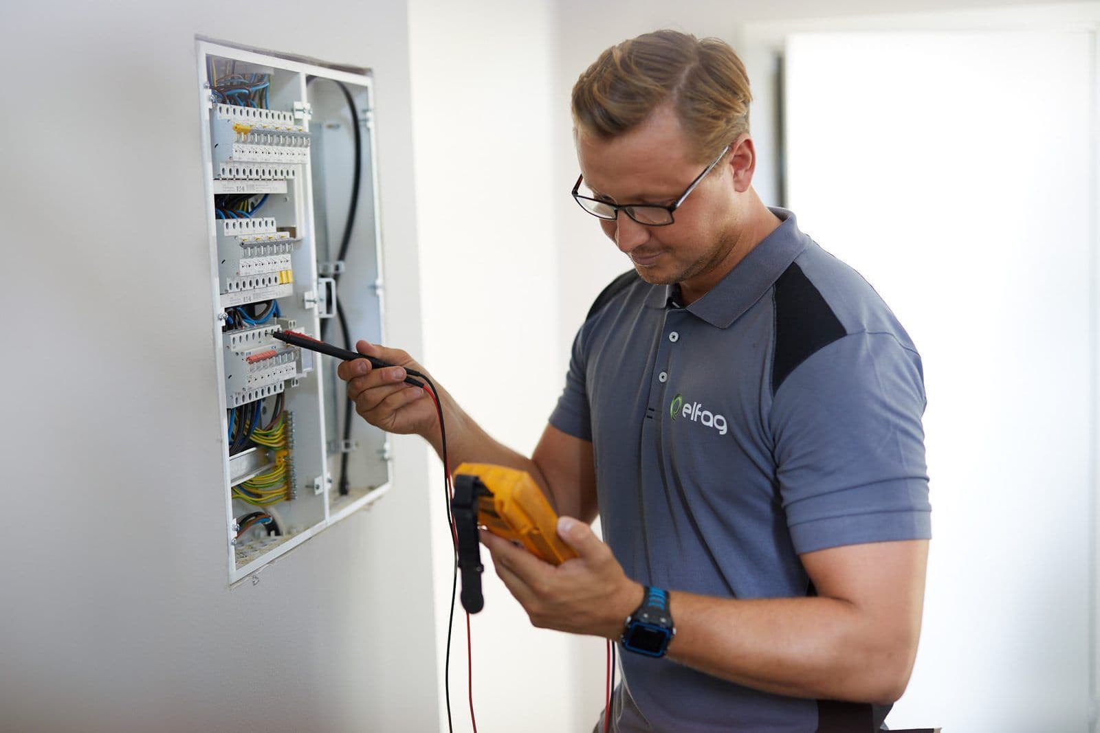 Elektriker måler i sikringsskapet med multimeter under internkontroll