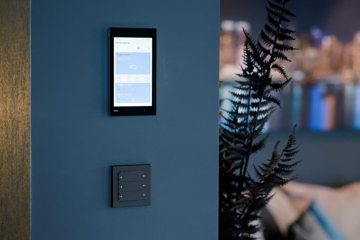Veggpanel for smarthusstyring ved siden av en KNX-bryter med flere trykkpunkter
